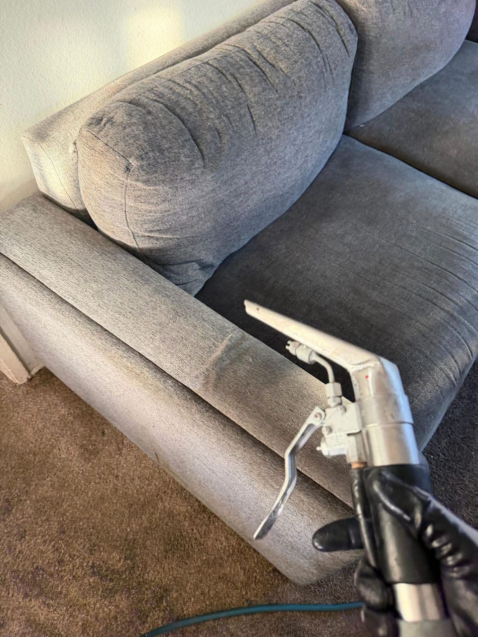 Mexi Maids technician steam cleaning a gray upholstered sofa
