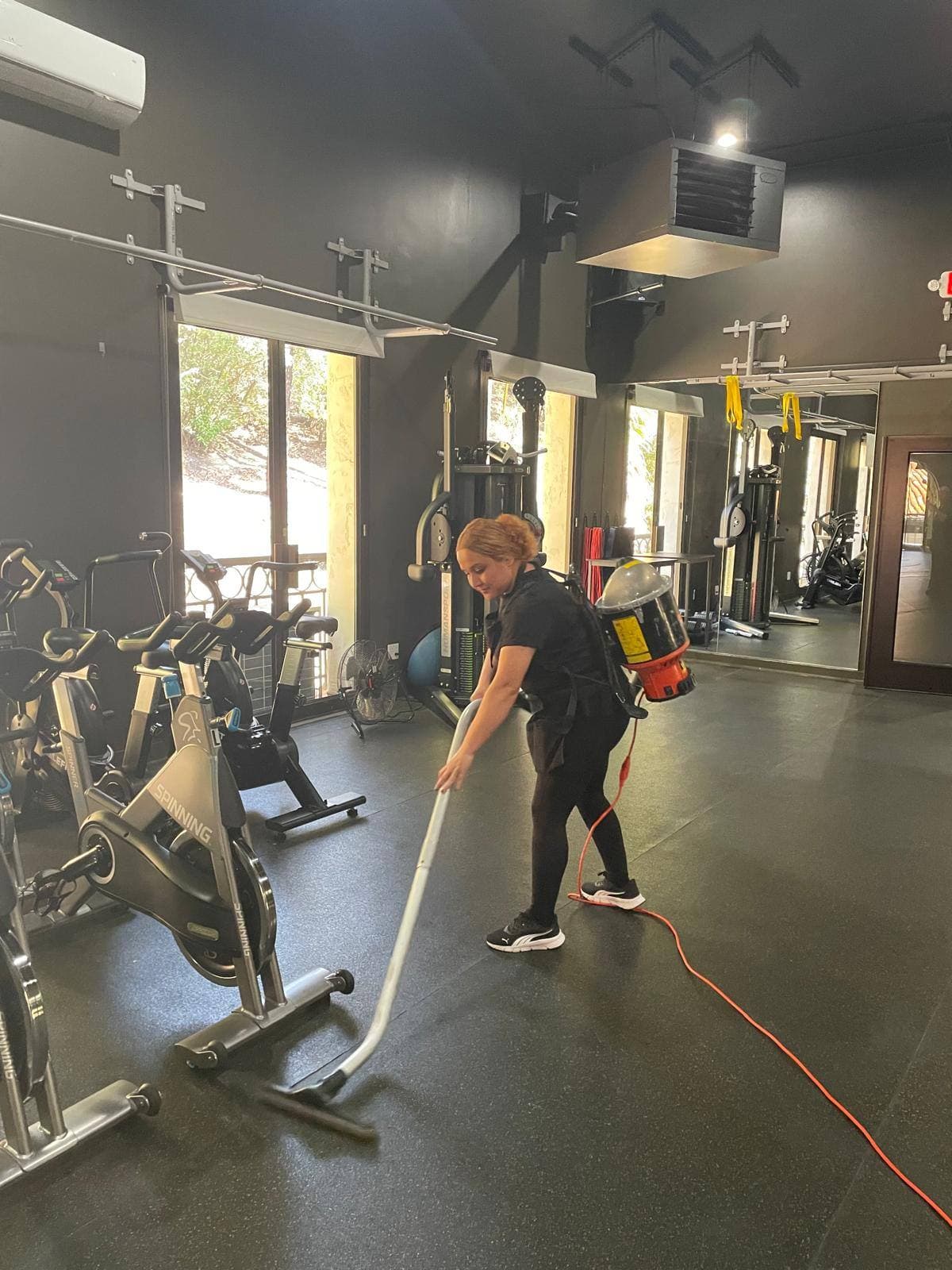 Team member vacuuming a fitness facility with a backpack vacuum